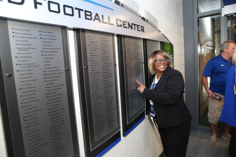A guest pointing at their name on the donor wall at the Jamie Hosford Football Center dedication.